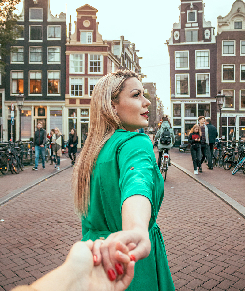 A solo traveler explores Amsterdam while holding hands with another traveler.