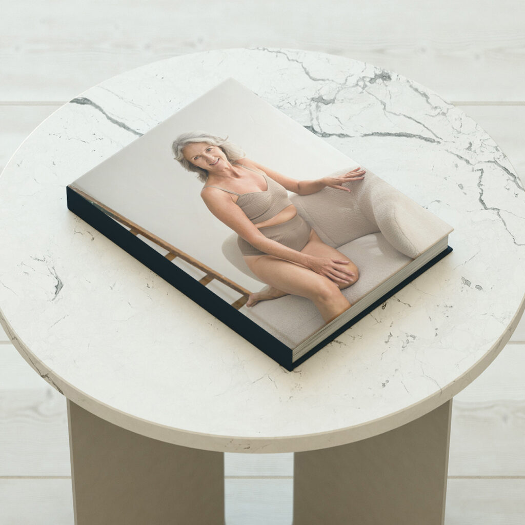 On a table, a boudoir photography album shows an old woman looking confident during her photoshoot.