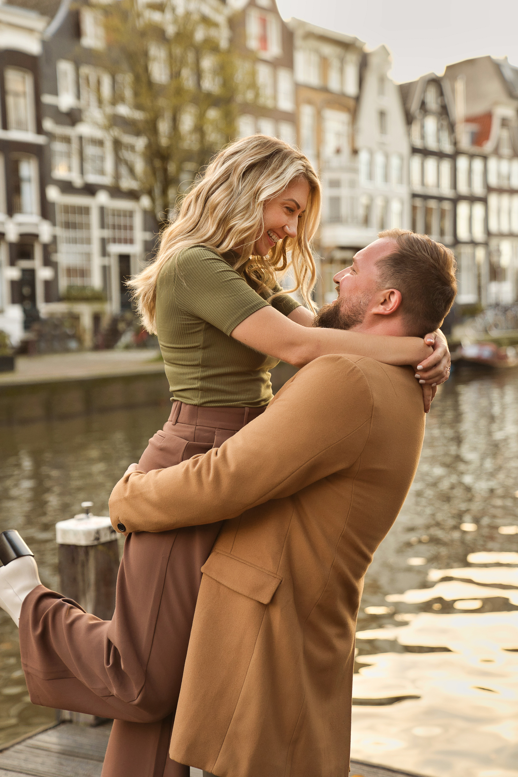 A man is smiling and holding up his newly fiancée in Amsterdam's canals.