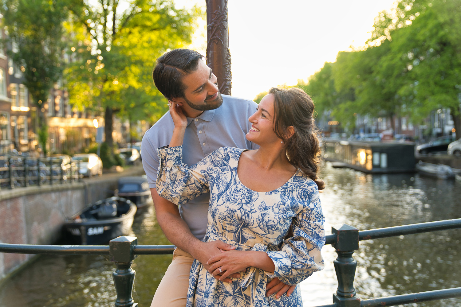 A couple is romantically hugging and smiling at each other in Amsterdam's canals while doing an engagement shoot.