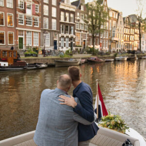 A gay couple enjoying a private boat in Amsterdam during their proposal photoshoot.