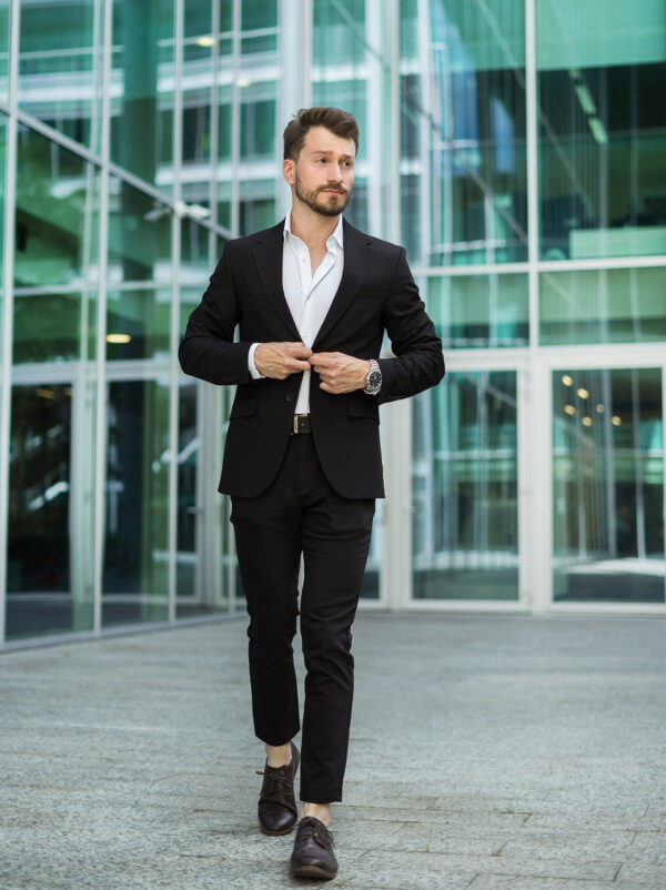 A man walking in an elegant black suit for his Tinder LinkedIn photo.