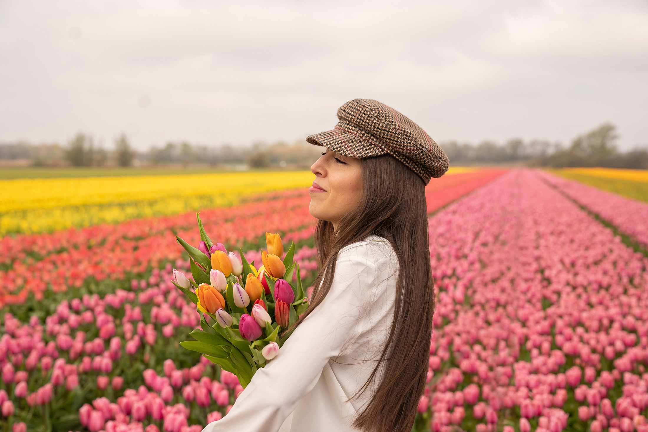 Tulip garden photo idea of a woman with a tulip bouquet surrounded by colorful tulip fields.