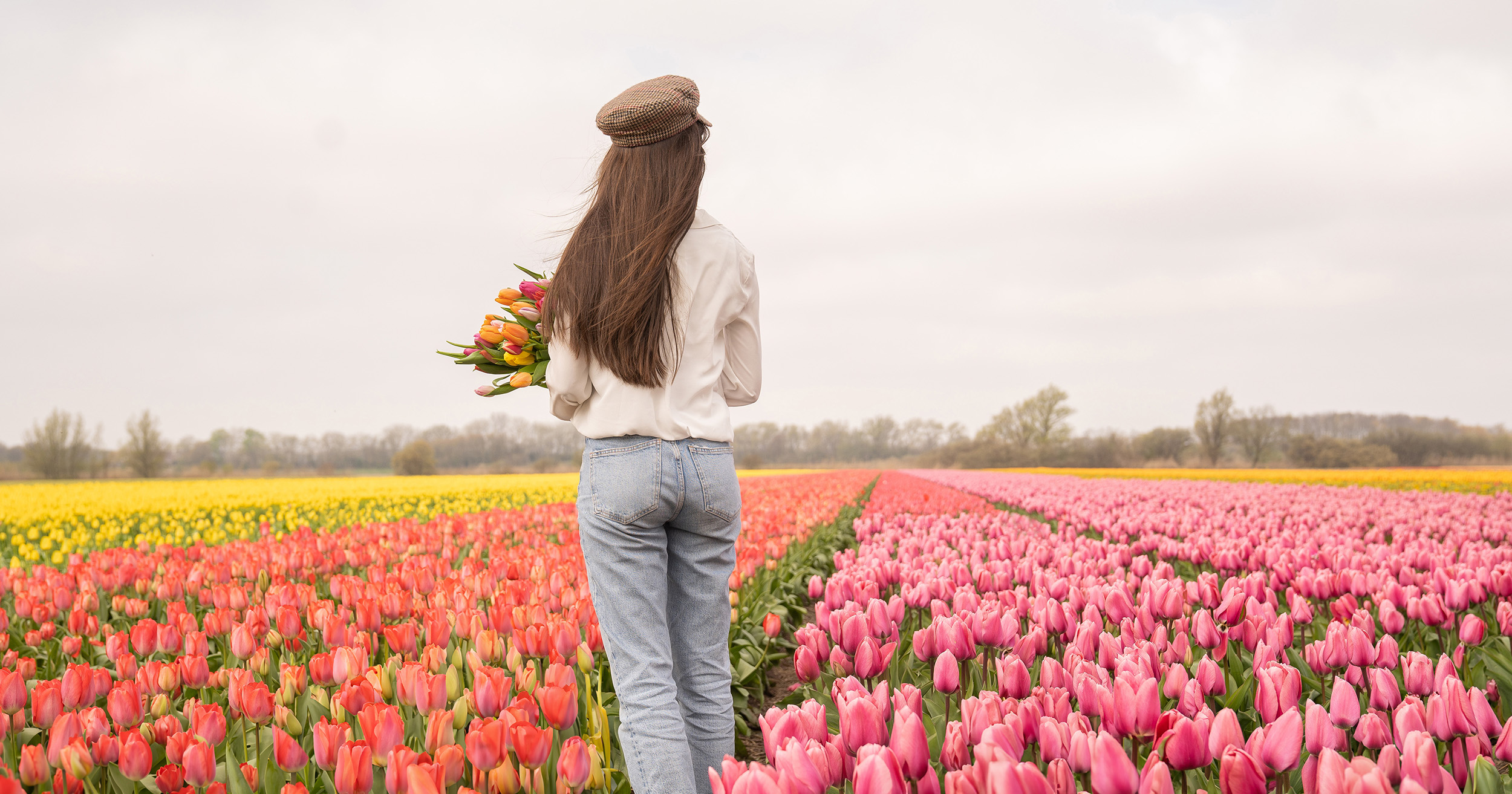 Tulip garden photo idea of a woman with a tulip bouquet surrounded by colorful tulip fields.